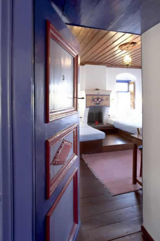 Les chambres de la Guesthouse à Papigo, une maison traditionnelle ont conservé l'architecture traditionnelle avec la cheminée qui domine la salle, entre les deux canapés